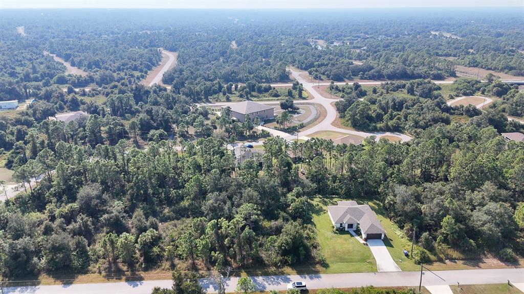 An aerial view shows a single-story house surrounded by dense trees and paved roads — FILBERT STREET, NORTH PORT, FL