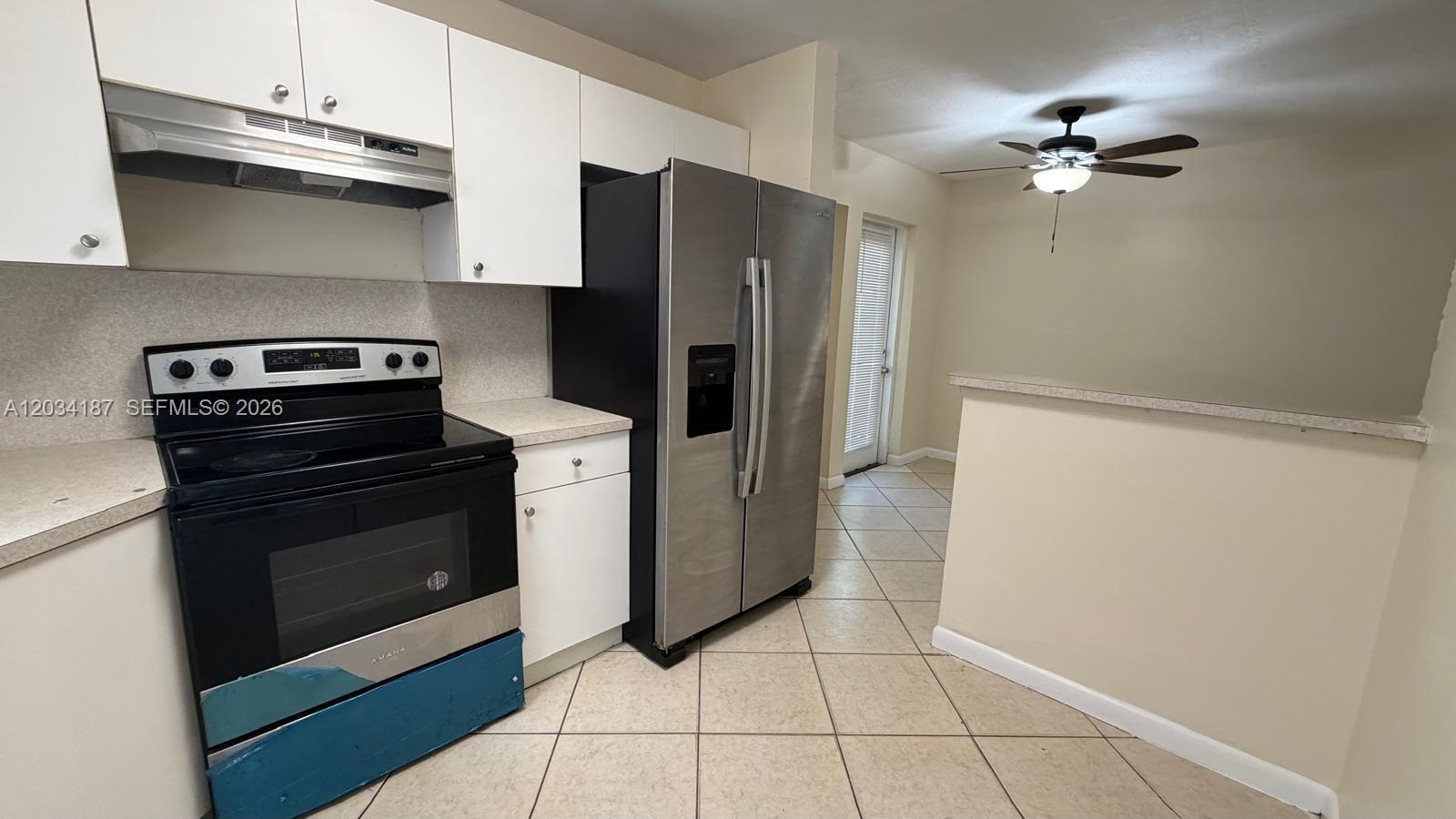 A kitchen features white cabinets, stainless steel appliances, and tile flooring — 1130 NW 43rd Ter # 0, Lauderhill FL 33313, LAUDERHILL, FL