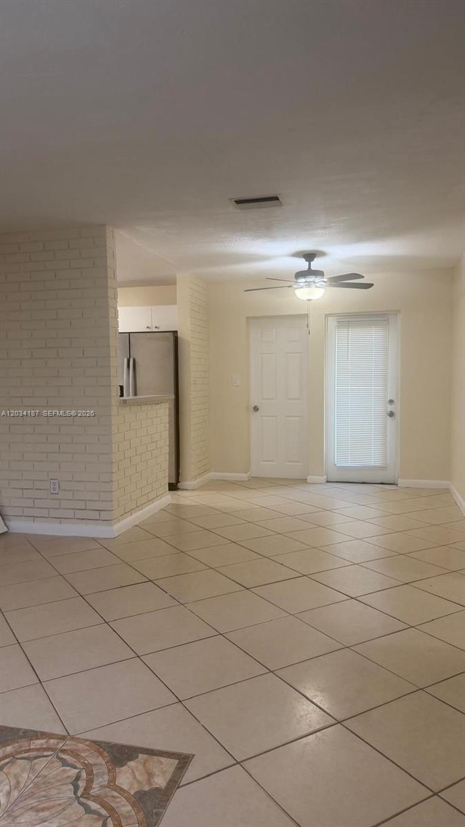 This room features light-colored tile flooring, a brick accent wall, and a ceiling fan — 1130 NW 43rd Ter # 0, Lauderhill FL 33313, LAUDERHILL, FL