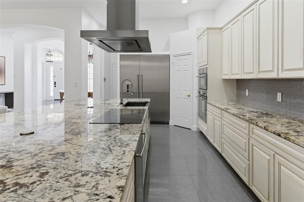 A modern kitchen features granite countertops, white cabinetry, stainless steel appliances, and gray tile flooring — 12513 SCARLETT SAGE COURT, WINTER GARDEN, FL