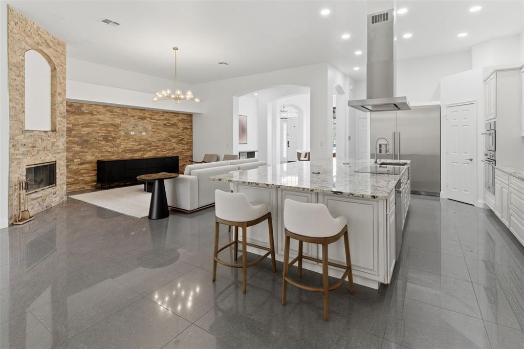 An open-concept kitchen and living area features a stone fireplace, granite island, and gray tile — 12513 SCARLETT SAGE COURT, WINTER GARDEN, FL