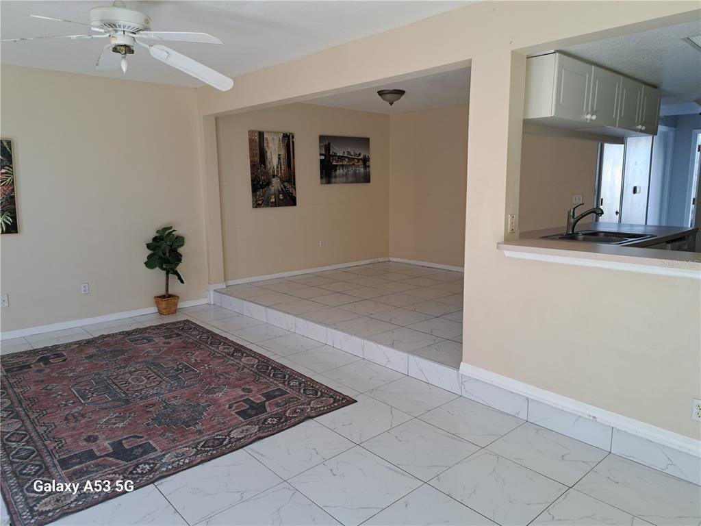 A living room and dining area feature white tile flooring, a raised platform, and a ceiling fan — 153 MANGO DRIVE, DAVENPORT, FL