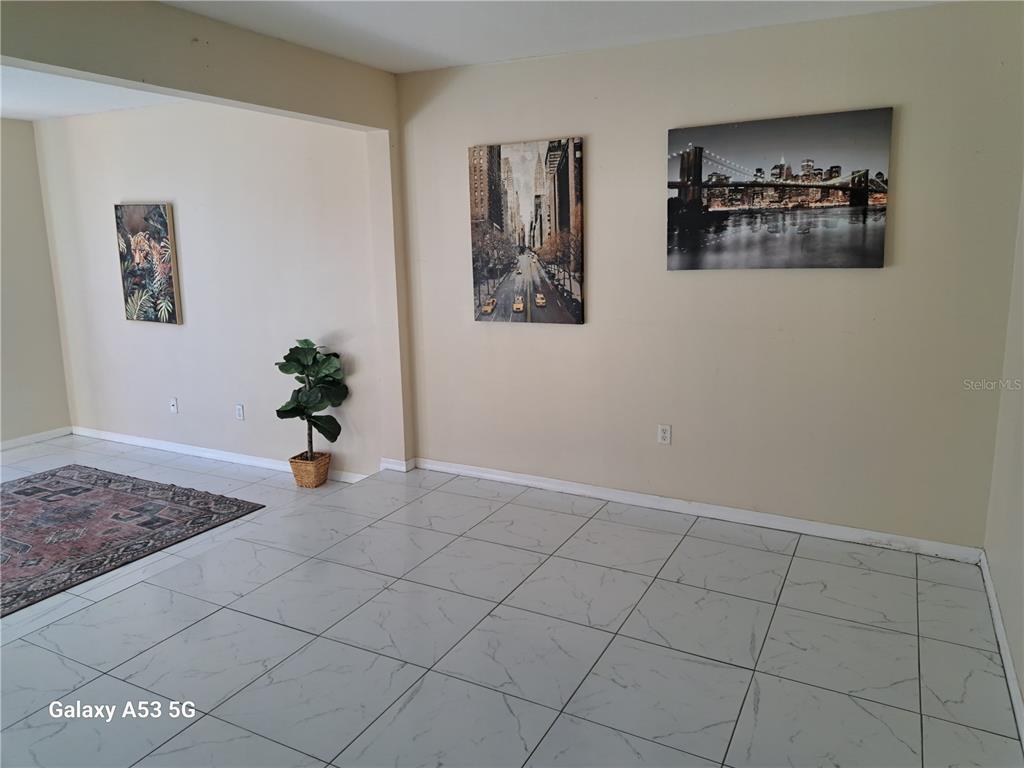A room with white tiled floors, beige walls, and three framed wall art pieces — 153 MANGO DRIVE, DAVENPORT, FL