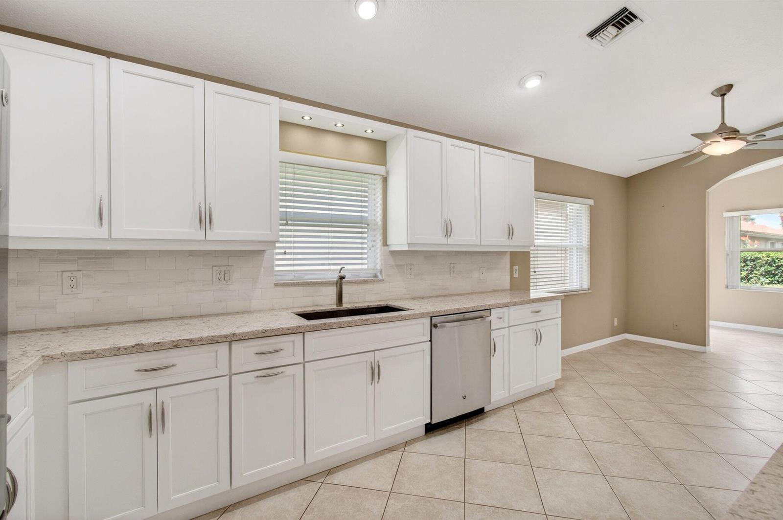 A kitchen with white cabinets, granite countertops, stainless steel appliances, and beige tile flooring — 11583 Ballylee Terrace, Boynton Beach FL 33437, BOYNTON BEACH, FL