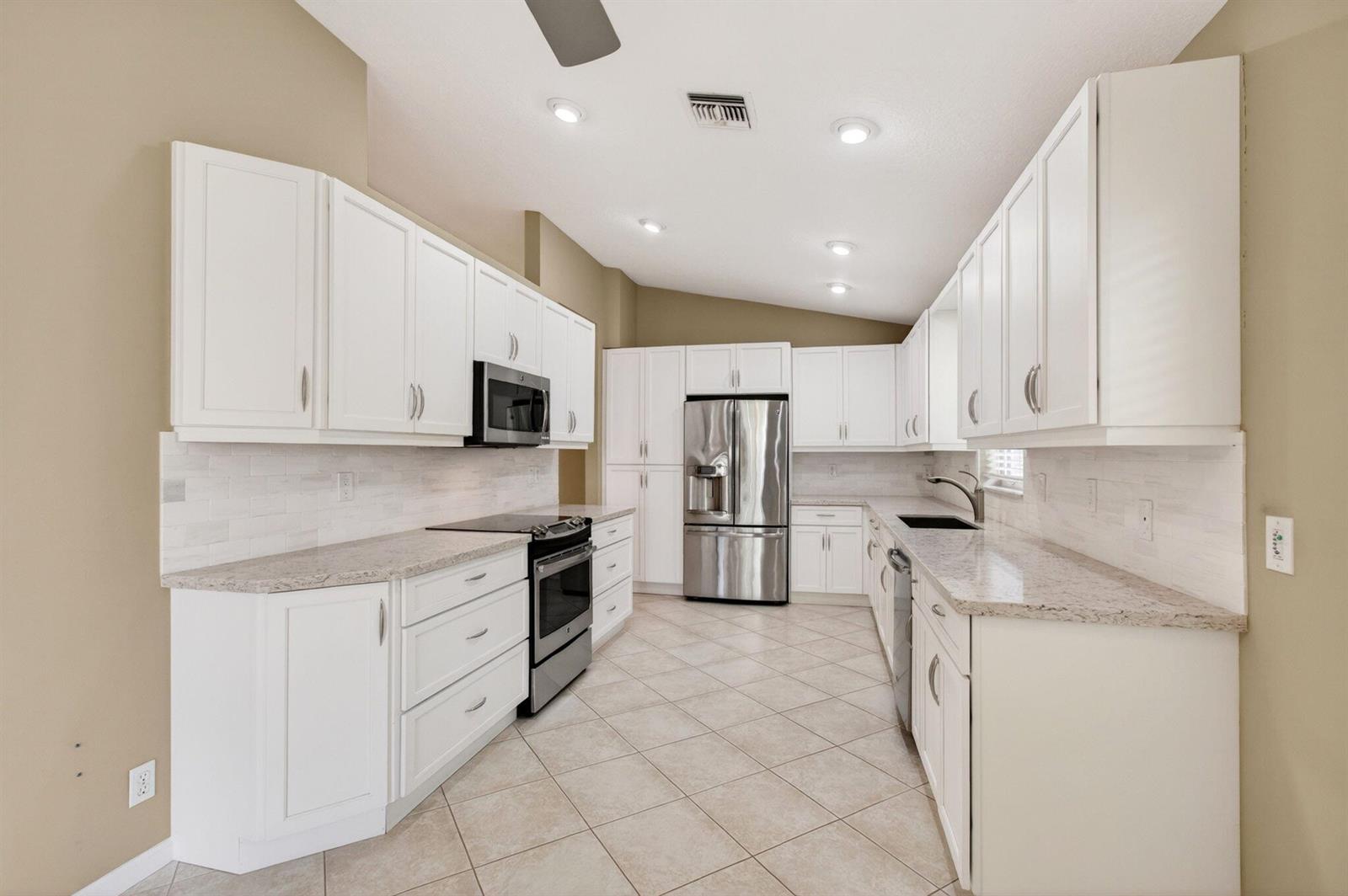 A kitchen with white cabinets, stainless steel appliances, granite countertops, and light-colored tile flooring — 11583 Ballylee Terrace, Boynton Beach FL 33437, BOYNTON BEACH, FL