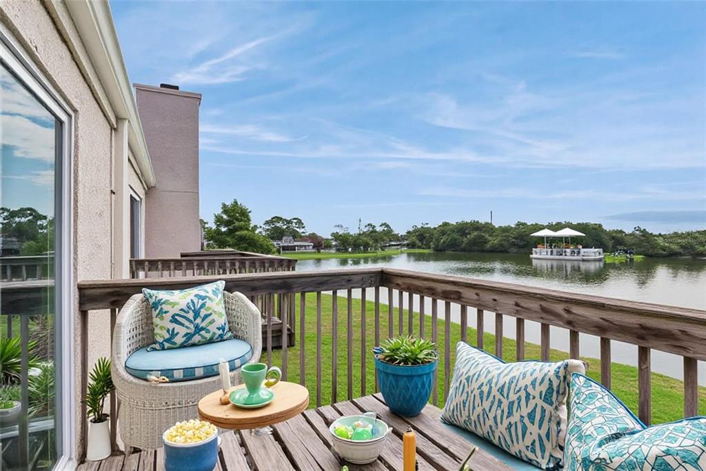 A wooden balcony with patio furniture overlooks a lake with a boat — 214 MAJORS LANE UNIT C, KISSIMMEE, FL