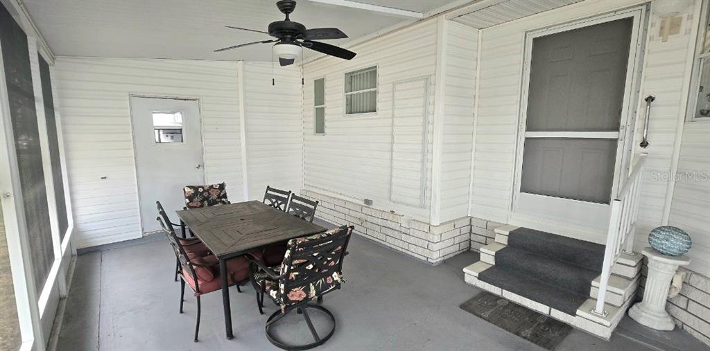 A covered patio features a dining set, a ceiling fan, and steps leading to a door — 31 REVERE WAY UNIT 23, PALM HARBOR, FL