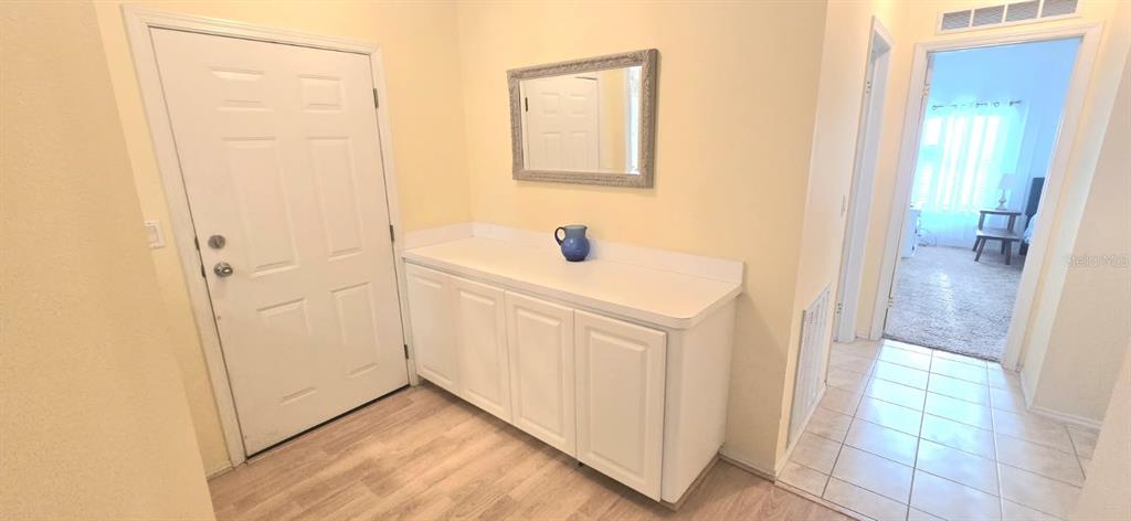 An entryway features a white door, a white cabinet with a mirror, and tiled flooring — 31 REVERE WAY UNIT 23, PALM HARBOR, FL