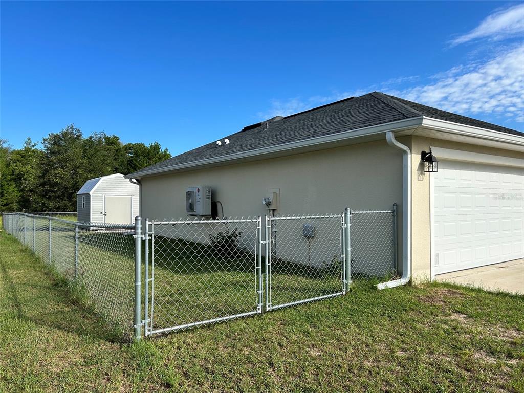 The exterior of a house features a chain-link fence, a storage shed, and a garage — 16750 SW 18TH AVENUE ROAD, OCALA, FL