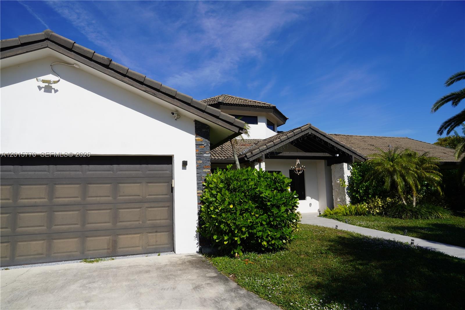 The exterior of a house features a garage, a tiled roof, and a landscaped yard — 18901 SW 50th ST, Southwest Ranches FL 33332, SOUTHWEST RANCHES, FL