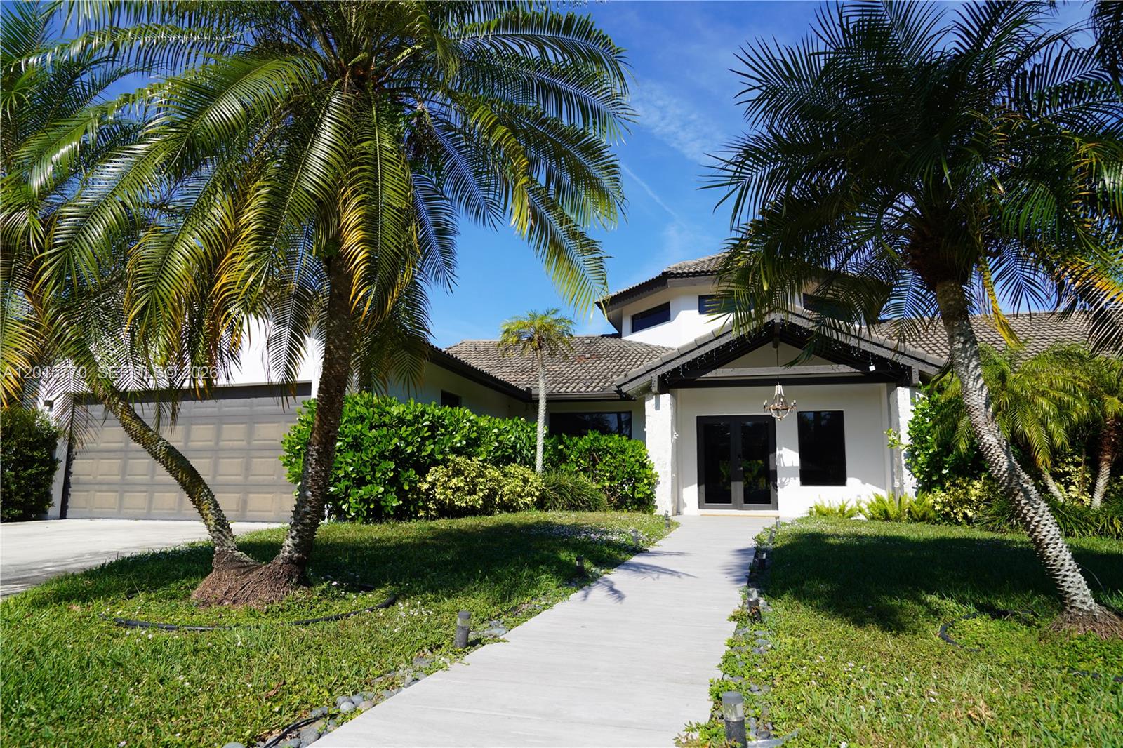 A single-story house with a white exterior, a tiled roof, and palm trees in the yard — 18901 SW 50th ST, Southwest Ranches FL 33332, SOUTHWEST RANCHES, FL