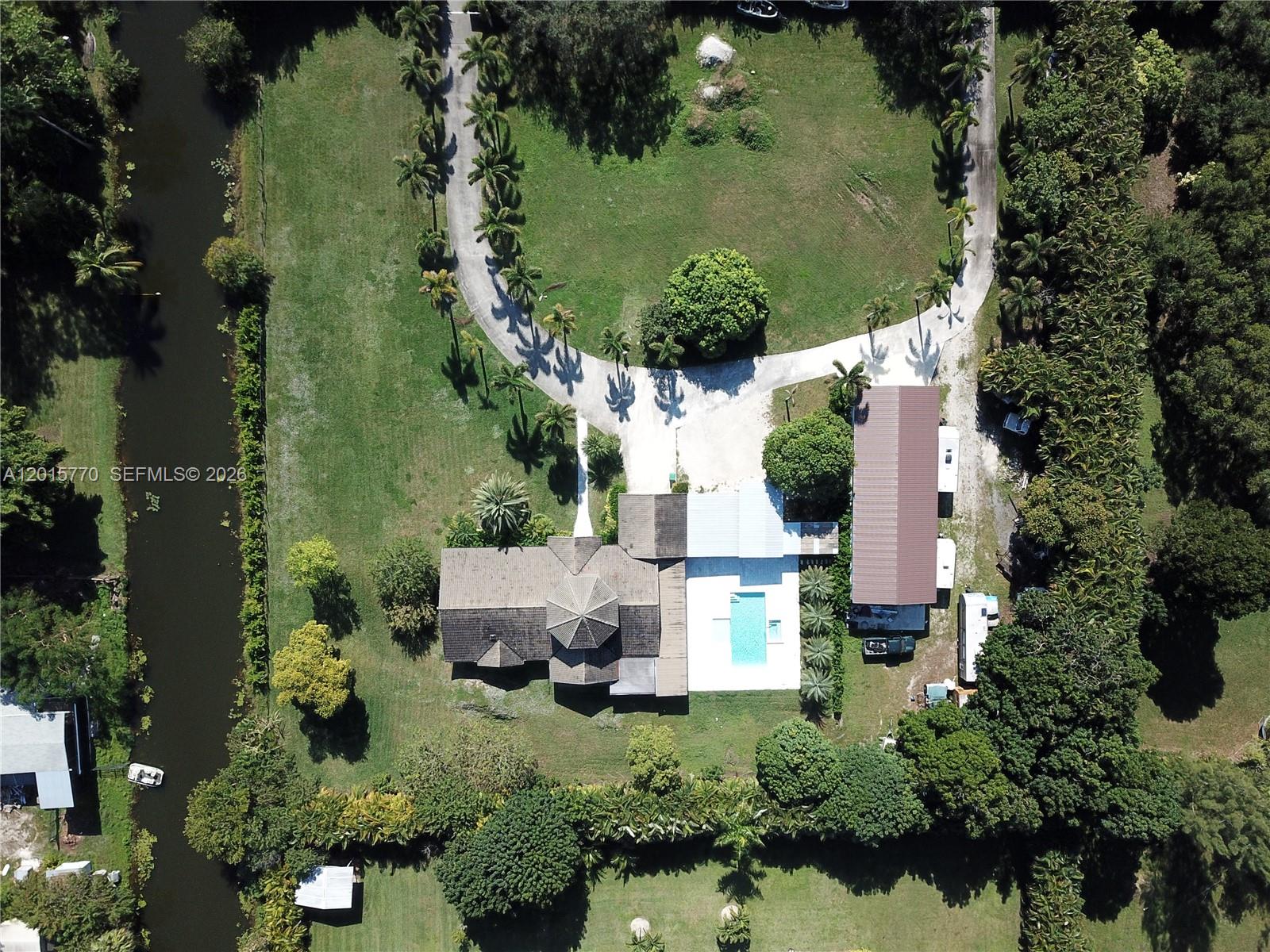 An aerial view shows a house with a pool, a long driveway, and a canal — 18901 SW 50th ST, Southwest Ranches FL 33332, SOUTHWEST RANCHES, FL