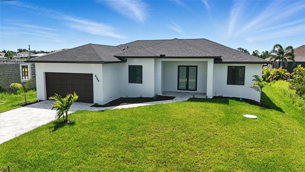 A single-story house with white stucco walls, a dark roof, and a paved driveway — 8348 WALDEN STREET, PORT CHARLOTTE, FL