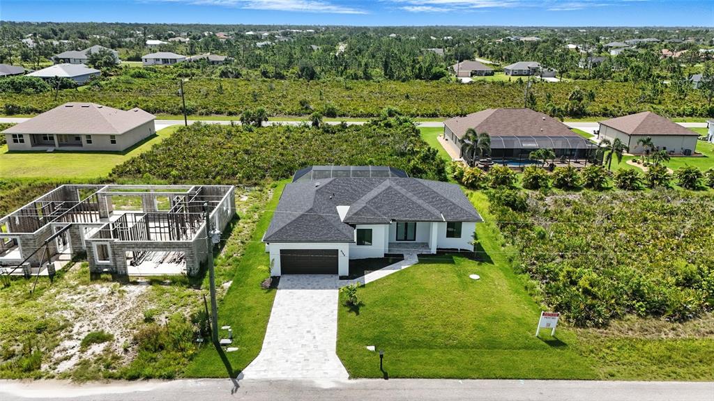 An aerial view shows a modern single-family home with a dark roof and paved driveway — 8348 WALDEN STREET, PORT CHARLOTTE, FL