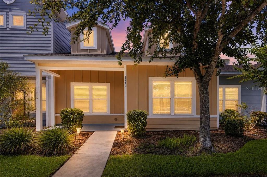 A tan house exterior features a covered front porch, two dormer windows, and a walkway — 2242 NW 51ST AVENUE, GAINESVILLE, FL