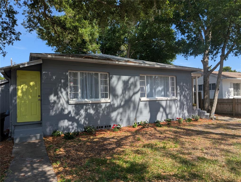 A gray single-story house features a bright yellow front door and two large windows — 3834 DR MARTIN LUTHER KING JR STREET S, ST PETERSBURG, FL