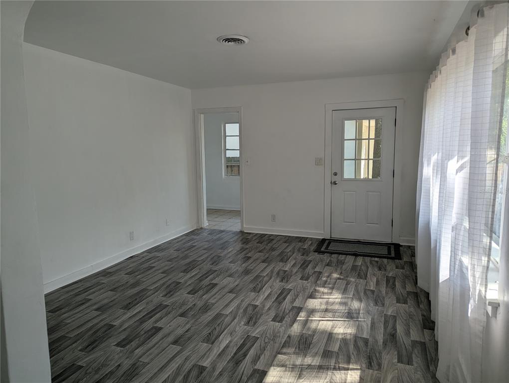 A bright room features gray wood-look flooring, white walls, and a white exterior door — 3834 DR MARTIN LUTHER KING JR STREET S, ST PETERSBURG, FL