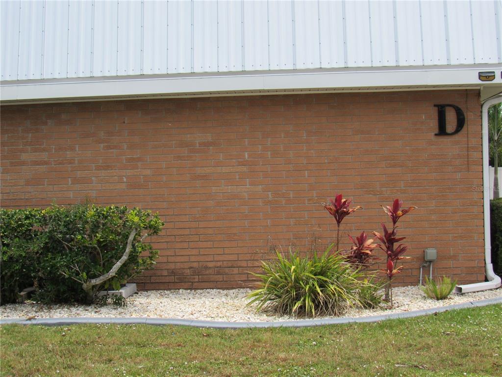 A brick exterior wall of a building marked with the letter D above landscaping — 22333 EDGEWATER DRIVE UNIT D-5, PUNTA GORDA, FL
