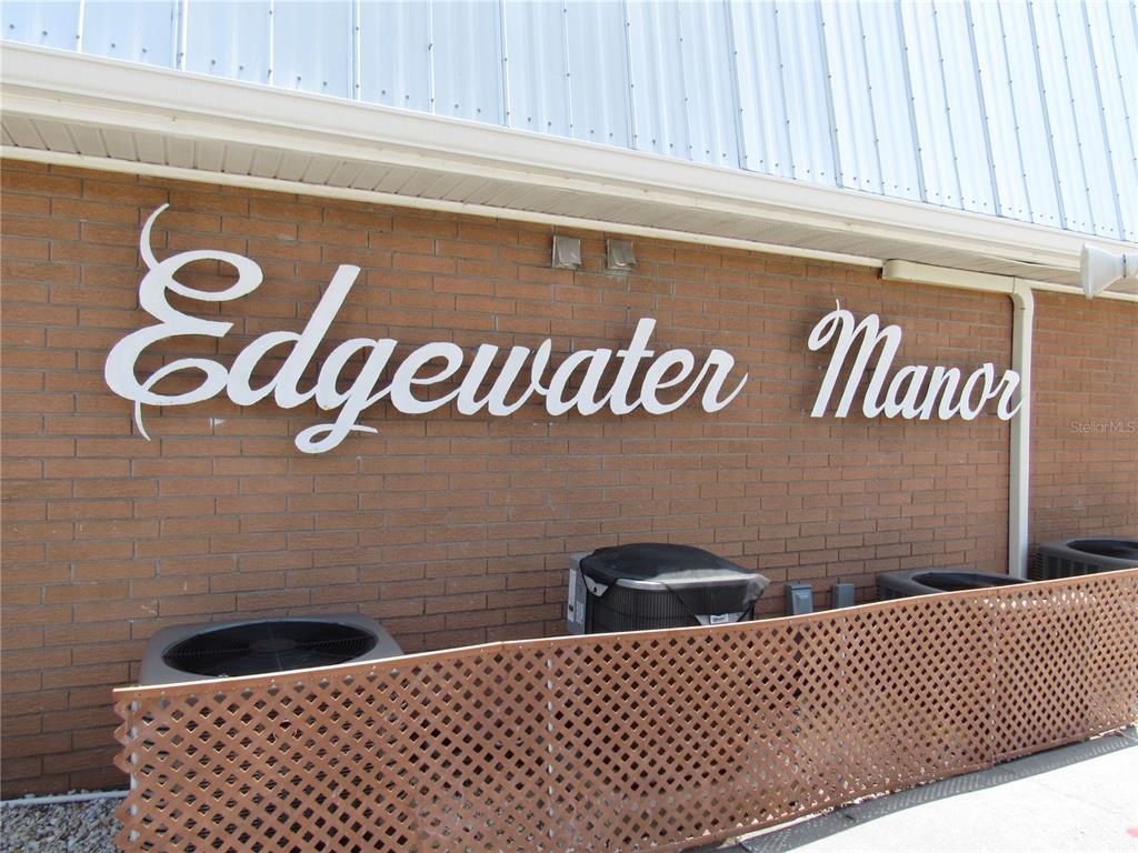 The exterior brick wall of a building features the sign Edgewater Manor and air conditioning units — 22333 EDGEWATER DRIVE UNIT D-5, PUNTA GORDA, FL