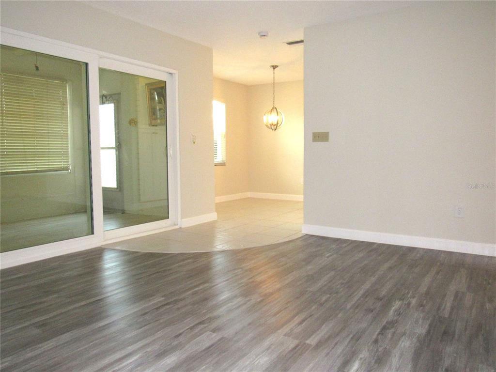 A room with wood-look flooring transitions to a tiled dining area featuring a pendant light — 22333 EDGEWATER DRIVE UNIT D-5, PUNTA GORDA, FL