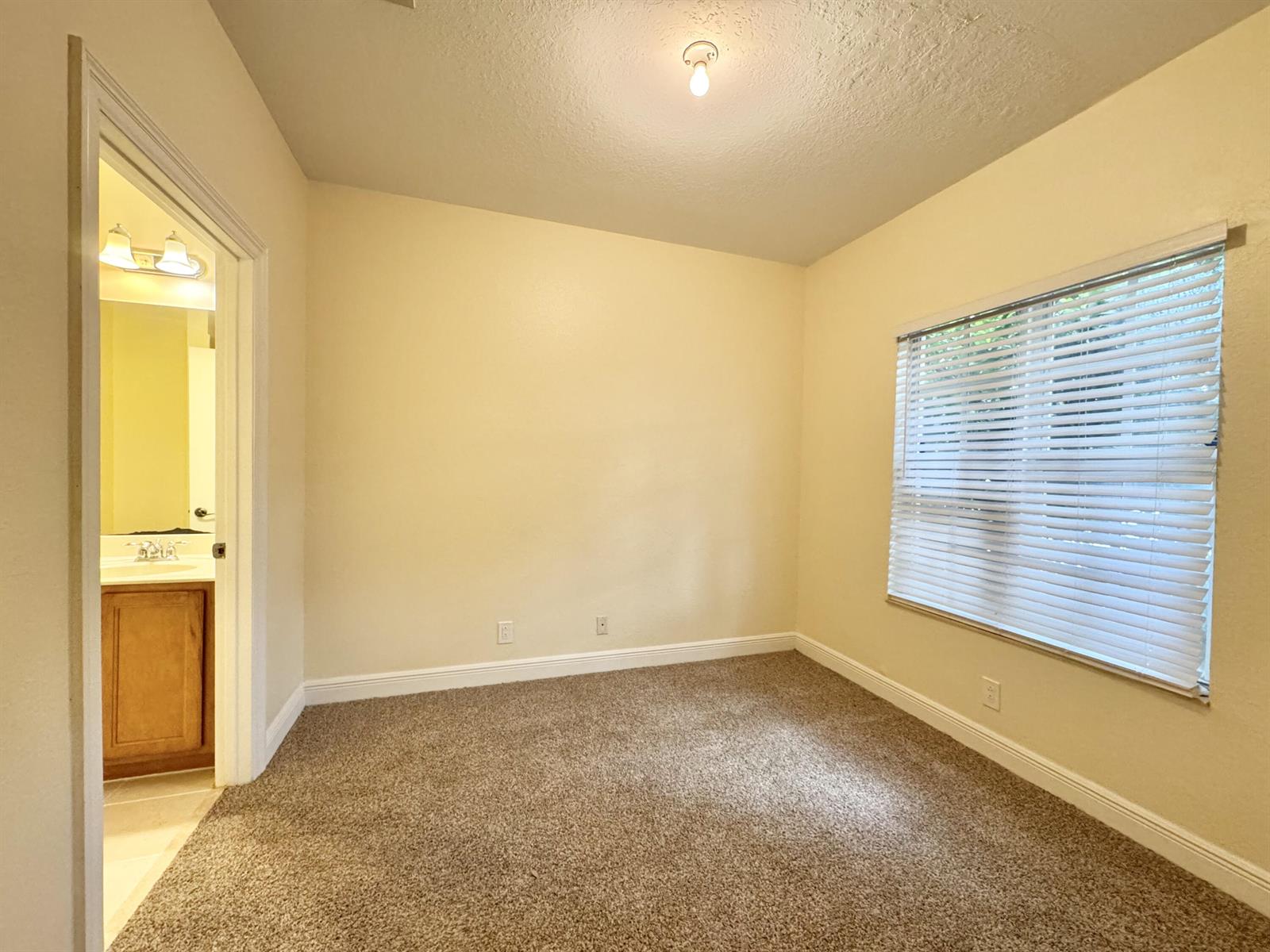 A bedroom with beige walls, carpeted flooring, a window with blinds, and an attached bathroom — 531 S Federal Highway # 15, FL 33460, FL
