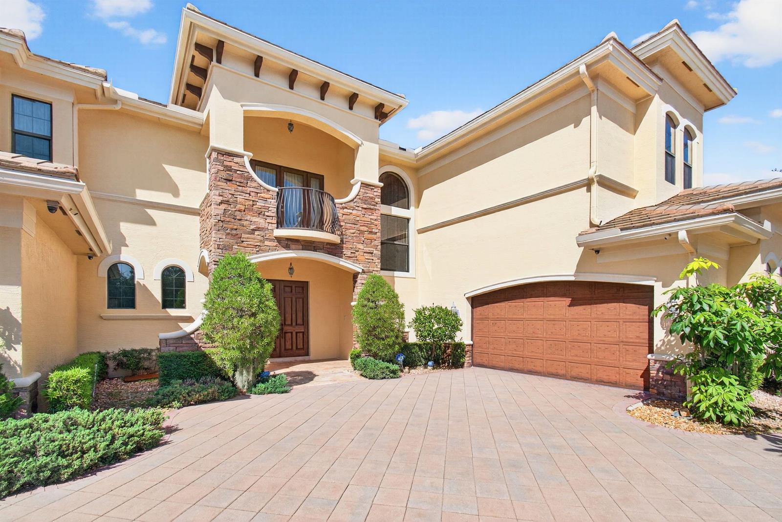 A two-story house with a stone facade, arched windows, a balcony, and a paved driveway — 9576 Equus Circle, Boynton Beach FL 33472, BOYNTON BEACH, FL