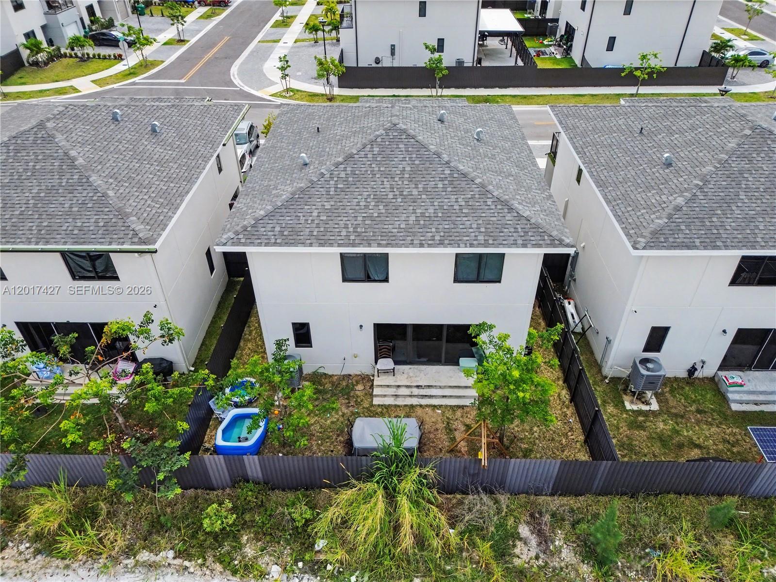 An aerial view shows the backyards and rear exteriors of three modern suburban houses — 227 NW 13th Pl, Florida City FL 33034, FLORIDA CITY, FL