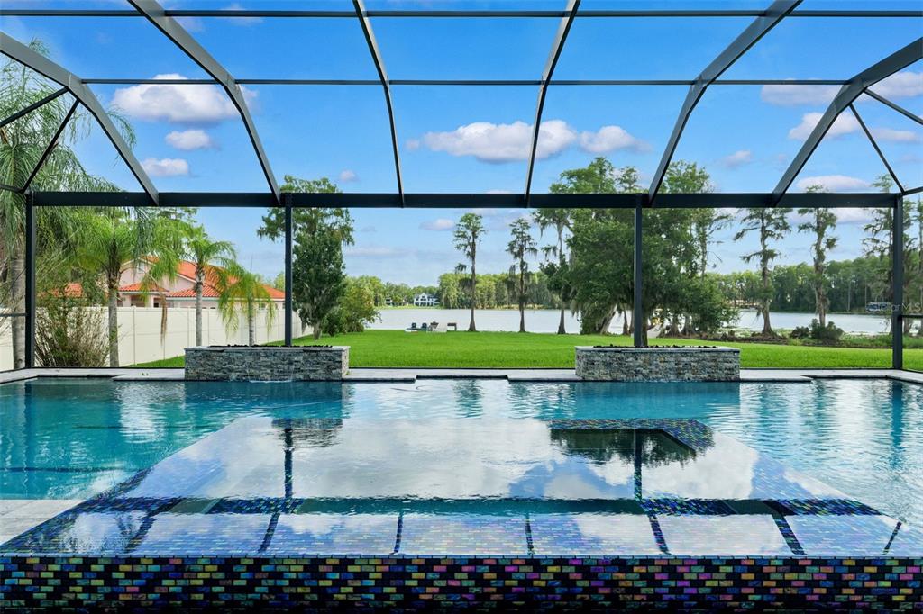A screened-in pool and spa overlook a grassy lawn and a lake — 5167 LAKECASTLE DRIVE, TAMPA, FL