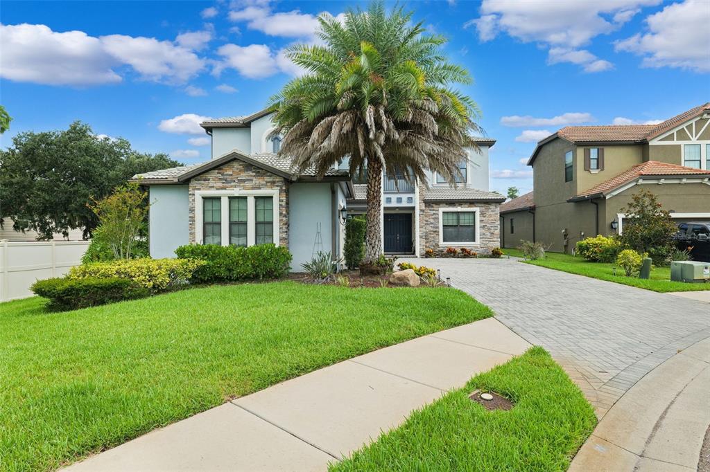 A two-story house with a stone facade, a palm tree, and a paved driveway — 5167 LAKECASTLE DRIVE, TAMPA, FL