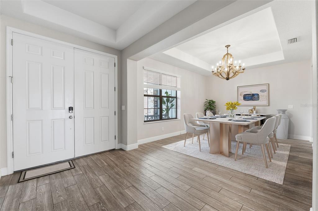 A dining room with a tray ceiling, chandelier, and wood-look tile flooring near an entryway — 5167 LAKECASTLE DRIVE, TAMPA, FL