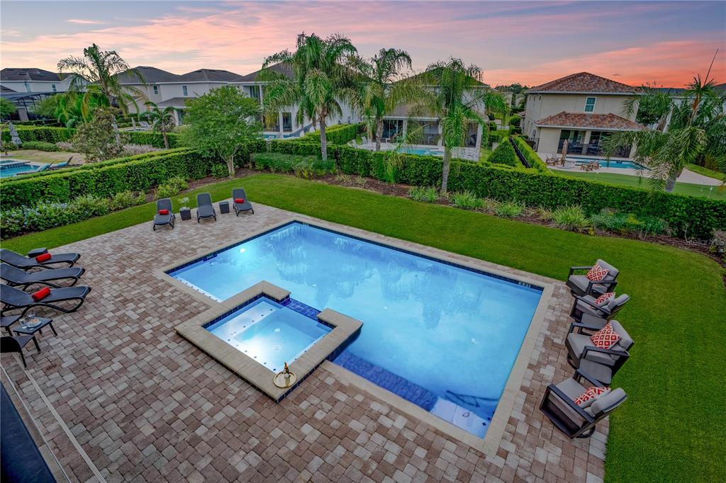 An aerial view of a backyard featuring a swimming pool, spa, and patio furniture — 7734 GRABEN STREET, KISSIMMEE, FL