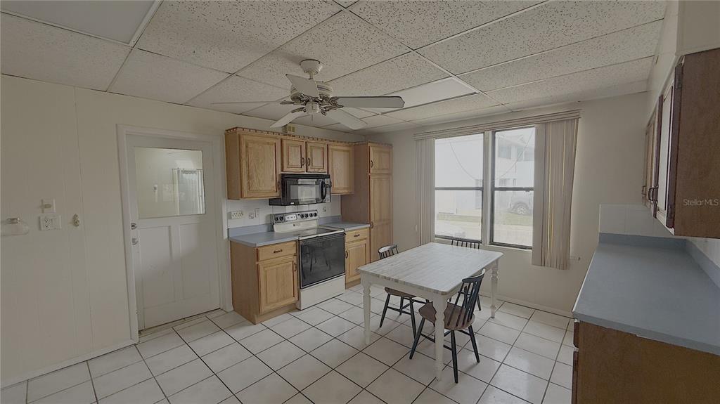 A kitchen with light wood cabinets, white tile floors, a ceiling fan, and a dining table — 500 S CENTRAL AVENUE, FLAGLER BEACH, FL