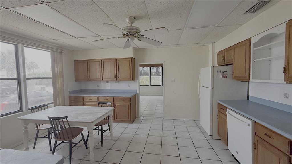 A kitchen with light-colored tile flooring, wood cabinets, a white table, and a ceiling fan — 500 S CENTRAL AVENUE, FLAGLER BEACH, FL