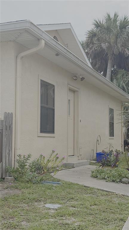 A side view of a beige stucco house with a sidewalk and small garden beds — 500 S CENTRAL AVENUE, FLAGLER BEACH, FL
