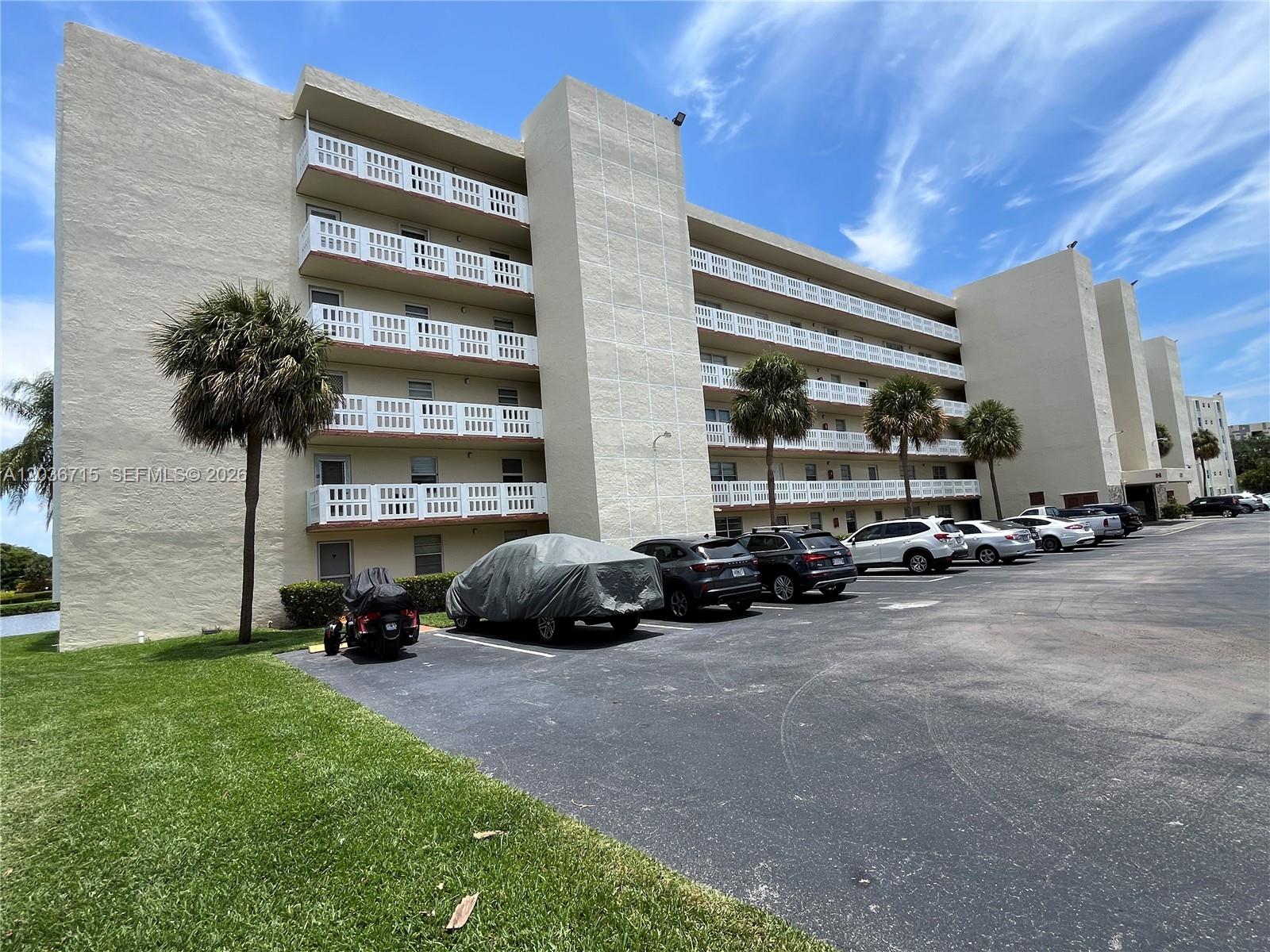 A multi-story apartment building with balconies and a parking lot in the foreground — 301 SE 3rd St # 204, Dania Beach FL 33004, DANIA BEACH, FL