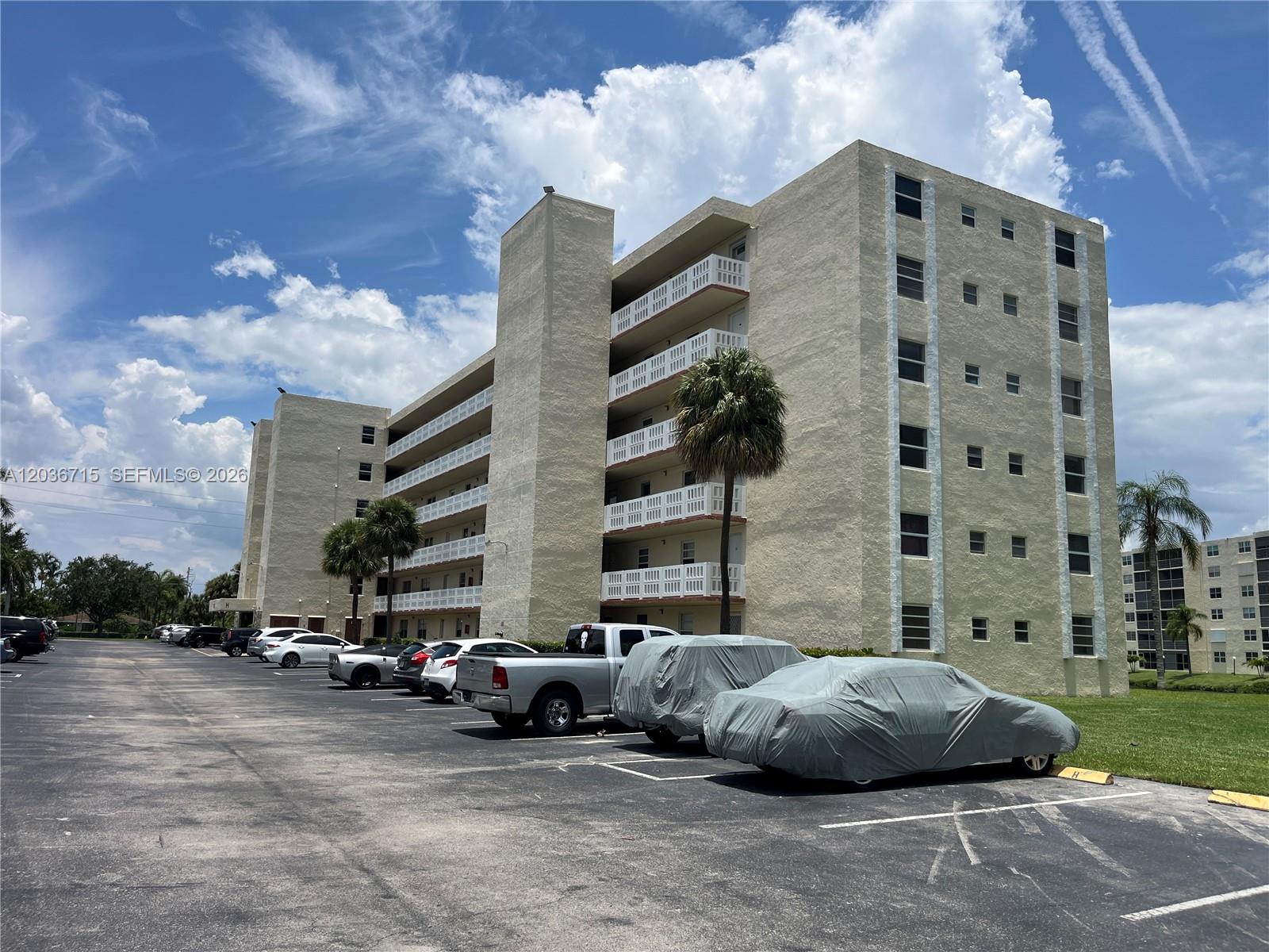 A multi-story apartment building with exterior balconies stands beside a parking lot with cars — 301 SE 3rd St # 204, Dania Beach FL 33004, DANIA BEACH, FL