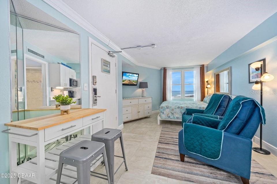 A hotel room features a bed, two blue armchairs, a desk, and an ocean view — 2301 S ATLANTIC AVENUE UNIT 201, DAYTONA BEACH, FL