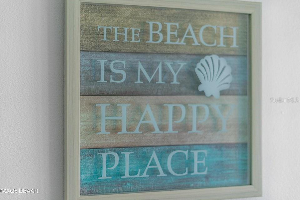 A framed wall sign reads "The beach is my happy place" with a seashell accent — 2301 S ATLANTIC AVENUE UNIT 201, DAYTONA BEACH, FL