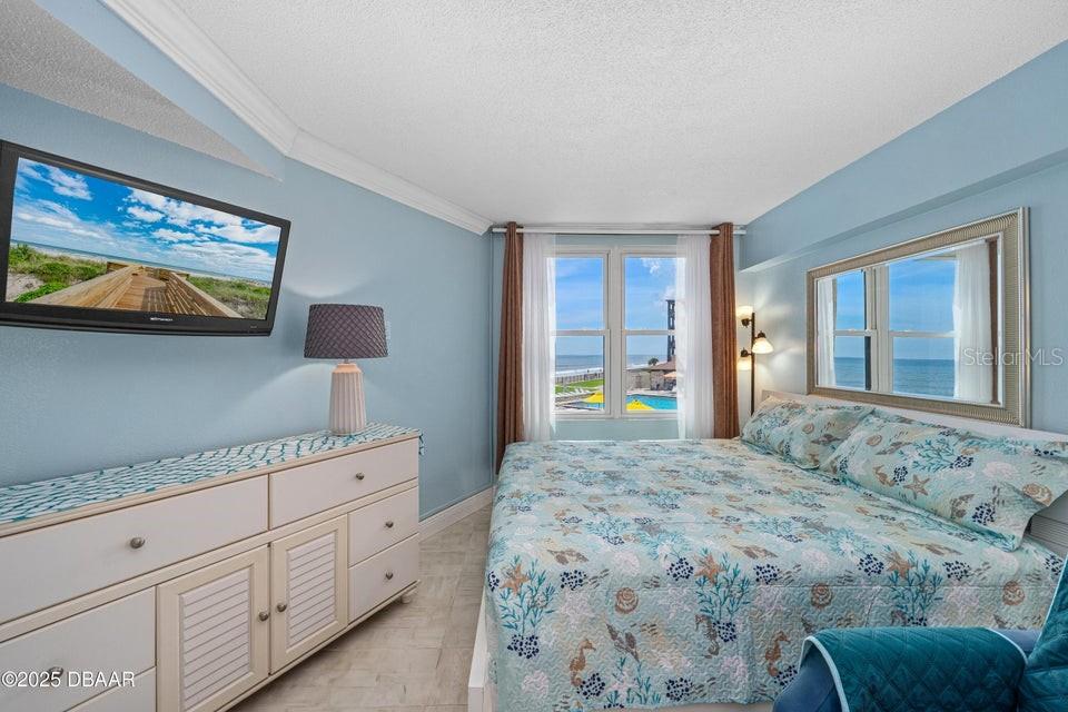 A bedroom features a king bed with coastal bedding, a white dresser, and ocean views — 2301 S ATLANTIC AVENUE UNIT 201, DAYTONA BEACH, FL