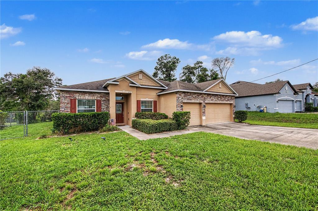A single-story suburban house with a stone facade, two-car garage, and a green lawn — 6545 LANDOVER BOULEVARD, SPRING HILL, FL