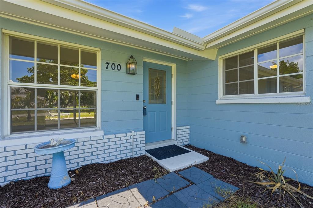 The exterior of a light blue house features a front door, windows, and brick accents — 700 DOLPHIN PARKWAY, PUNTA GORDA, FL