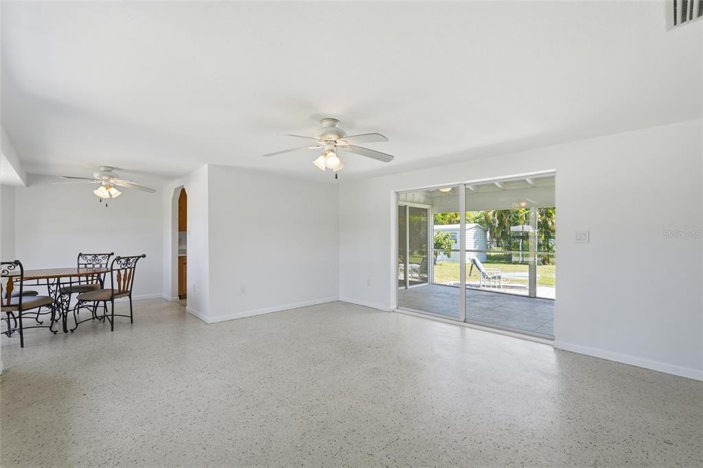 A dining area and living space with white walls, terrazzo floors, and sliding glass doors — 700 DOLPHIN PARKWAY, PUNTA GORDA, FL