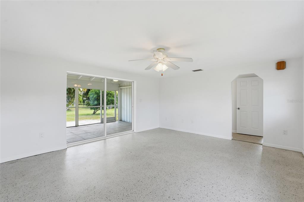A bright, empty room with white walls, a speckled floor, and sliding glass patio doors — 700 DOLPHIN PARKWAY, PUNTA GORDA, FL