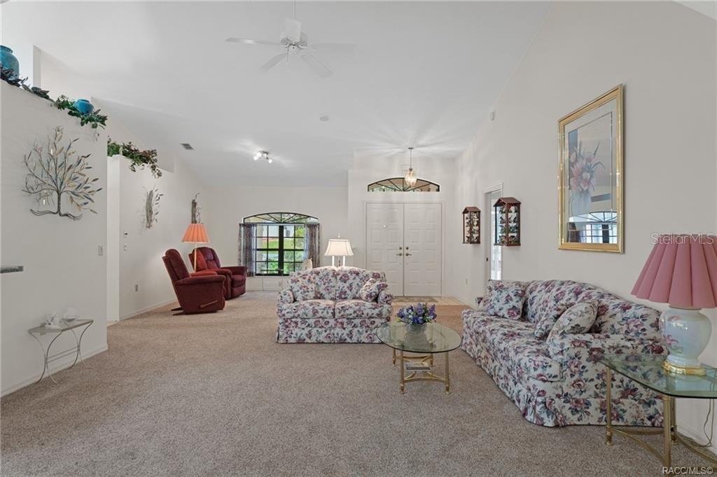 A living room features vaulted ceilings, floral sofas, red recliners, and a glass coffee table — 3116 N STRATHAM POINT, HERNANDO, FL