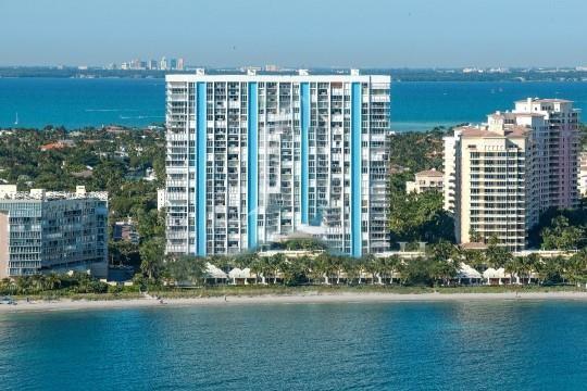 An aerial view shows a tall, blue-accented residential building situated along a sandy beach — 881 Ocean Dr, Key Biscayne FL 33149, KEY BISCAYNE, FL