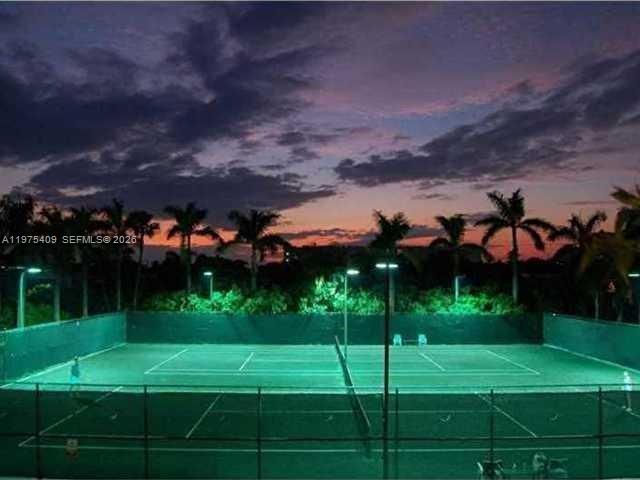 An outdoor tennis court is illuminated at night under a colorful sunset sky — 881 Ocean Dr, Key Biscayne FL 33149, KEY BISCAYNE, FL