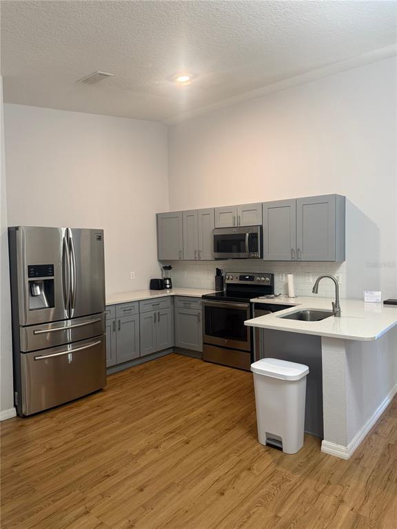 A kitchen features stainless steel appliances, gray cabinets, and a white countertop with a sink — 2774 CLUB CORTILE CIR UNIT B, KISSIMMEE, FL