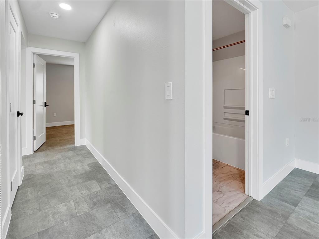 A hallway with gray tile flooring leads to a doorway and a bathroom entrance — 0000 LENOX BOULEVARD, ORLANDO, FL