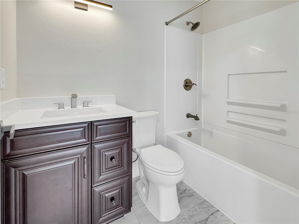 A bathroom features a dark wood vanity, white countertop, toilet, and a tub-shower combination — 0000 LENOX BOULEVARD, ORLANDO, FL