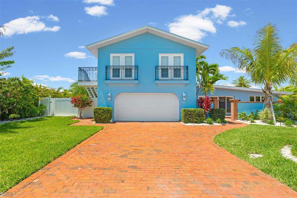 A two-story blue house features a brick driveway, a white garage door, and two balconies — 528 KEY ROYALE DRIVE, HOLMES BEACH, FL